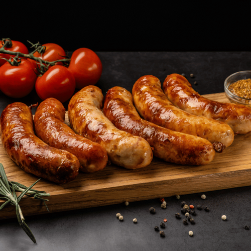 German bratwurst grilled and sliced on a wooden board with peppercorns and rosemary